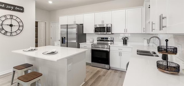 5768 Anders Way, Saint Cloud, FL 34771 - kitchen with appliances with stainless steel finishes, a sink, light wood-type flooring, a kitchen bar, and white cabinets