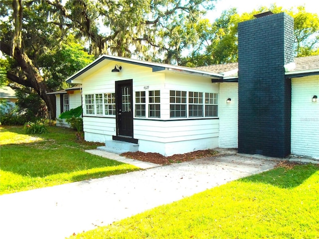 4629 Harden Blvd, Lakeland, FL 33813 - view of front of house with entry steps, a front yard, and a chimney
