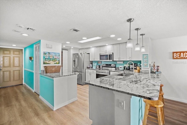 830 N Atlantic Ave Unit B502, Cocoa Beach, FL 32931 - kitchen featuring stainless steel appliances, a peninsula, light wood-type flooring, a kitchen breakfast bar, and a sink