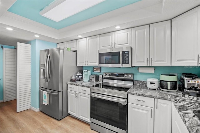 830 N Atlantic Ave Unit B502, Cocoa Beach, FL 32931 - kitchen with stainless steel appliances, a tray ceiling, crown molding, light wood finished floors, and recessed lighting