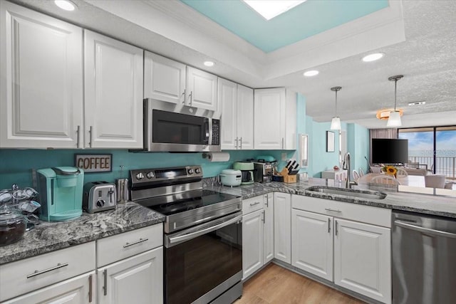830 N Atlantic Ave Unit B502, Cocoa Beach, FL 32931 - kitchen featuring stainless steel appliances, a sink, white cabinetry, light wood-style flooring, and hanging light fixtures