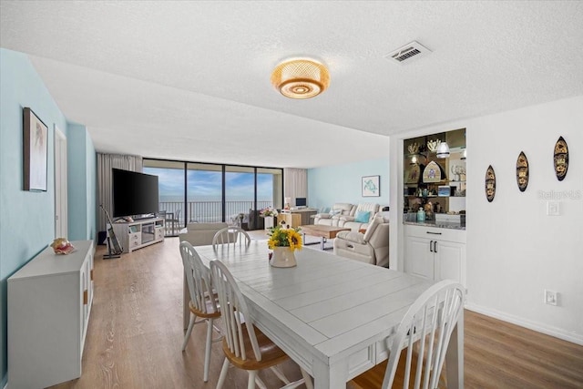 830 N Atlantic Ave Unit B502, Cocoa Beach, FL 32931 - dining area with wood finished floors, a wall of windows, a textured ceiling, and baseboards