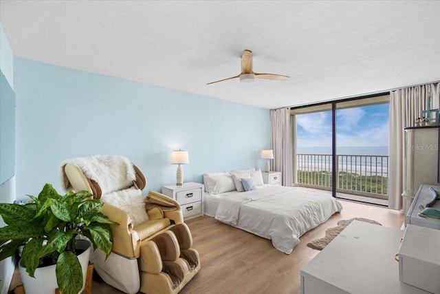 830 N Atlantic Ave Unit B502, Cocoa Beach, FL 32931 - bedroom featuring access to exterior, wood finished floors, a water view, expansive windows, and a ceiling fan