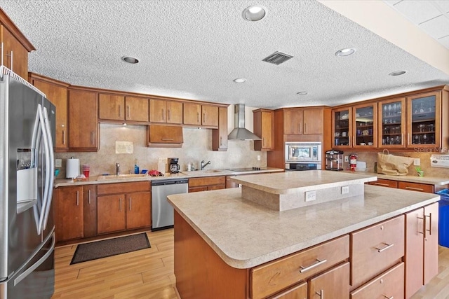 830 N Atlantic Ave Unit B502, Cocoa Beach, FL 32931 - kitchen with appliances with stainless steel finishes, wall chimney exhaust hood, a sink, a kitchen island, and light wood finished floors