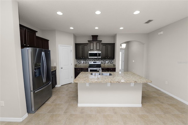 4125 Prima Lago Cir, Lakeland, FL 33810 - kitchen with stainless steel appliances, arched walkways, a center island with sink, recessed lighting, and tasteful backsplash