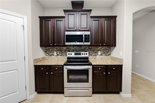 4125 Prima Lago Cir, Lakeland, FL 33810 - kitchen featuring appliances with stainless steel finishes, decorative backsplash, arched walkways, and dark brown cabinetry