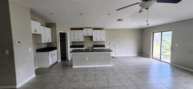 3188 Nubbin Ridge Ln, Zephyrhills, FL 33540 - kitchen featuring a sink, an island with sink, white cabinets, baseboards, and dark countertops