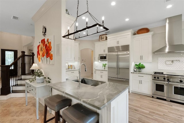 1825 Pawnee Trl, Lakeland, FL 33803 - kitchen featuring wall chimney exhaust hood, high end appliances, a sink, white cabinetry, and tasteful backsplash