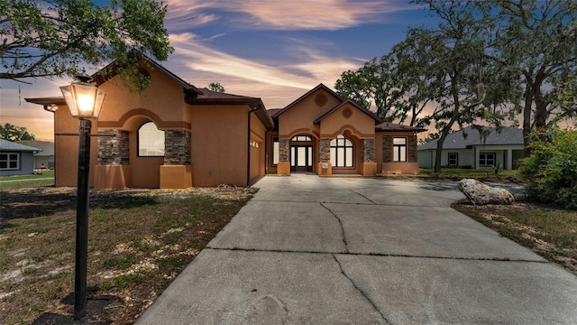 5370 Boxtree Ct, Dade City, FL 33523 - mediterranean / spanish home with stone siding, stucco siding, concrete driveway, and an attached garage