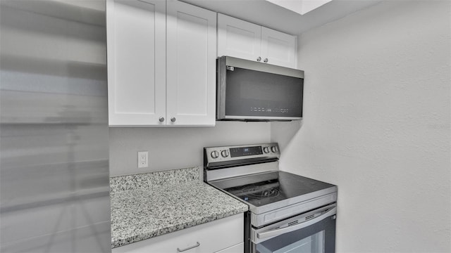 1017 Fleming Ave, Lakeland, FL 33815 - kitchen with appliances with stainless steel finishes, white cabinetry, and light stone counters
