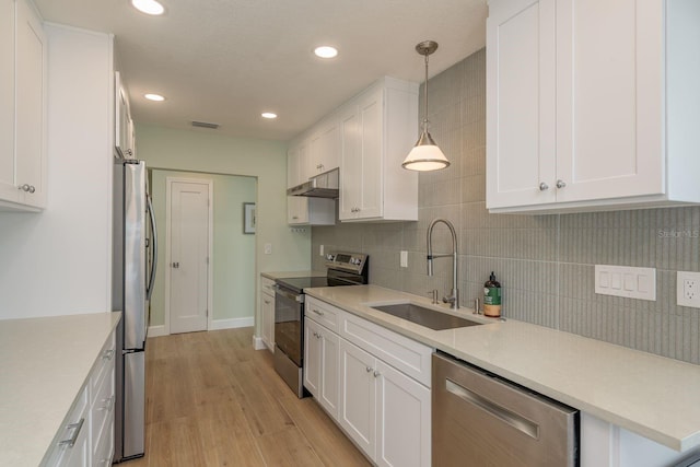 3626 Corsair Ct, New Port Richey, FL 34652 - kitchen with stainless steel appliances, a sink, backsplash, light wood-style floors, and white cabinetry