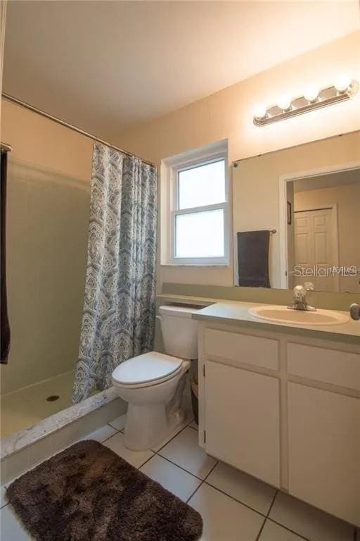 1410 Bramblewood Dr, Lakeland, FL 33811 - bathroom with tile patterned floors, toilet, vanity, and a shower with shower curtain