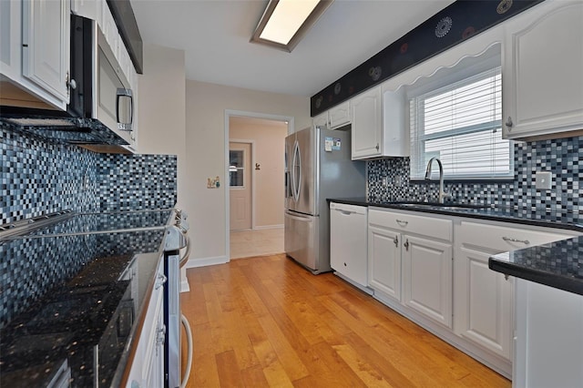 3487 Highland Fairways Blvd, Lakeland, FL 33810 - kitchen featuring appliances with stainless steel finishes, a sink, dark countertops, white cabinets, and tasteful backsplash