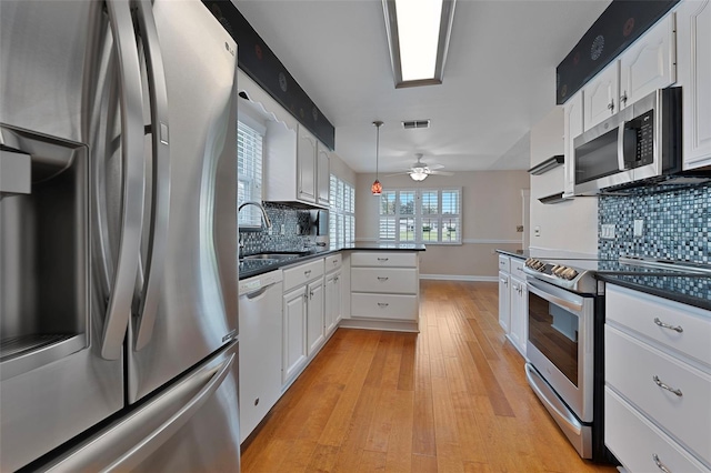 3487 Highland Fairways Blvd, Lakeland, FL 33810 - kitchen featuring appliances with stainless steel finishes, a sink, dark countertops, light wood-style flooring, and white cabinetry