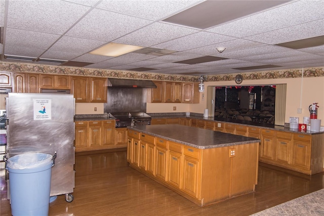 3487 Highland Fairways Blvd, Lakeland, FL 33810 - kitchen featuring freestanding refrigerator, under cabinet range hood, dark wood-type flooring, a kitchen island, and a drop ceiling