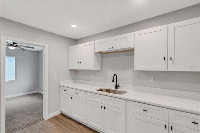 3601 Ave R NW, Winter Haven, FL 33881 - kitchen featuring a sink, white cabinets, light countertops, light wood-type flooring, and a ceiling fan