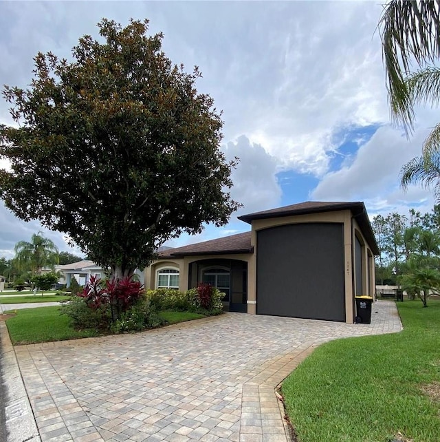 1167 Motorcoach Dr, Polk City, FL 33868 - view of front of home with stucco siding, a front yard, a garage, and decorative driveway