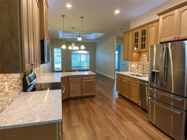 1167 Motorcoach Dr, Polk City, FL 33868 - kitchen featuring stainless steel appliances, a peninsula, a raised ceiling, a sink, and recessed lighting