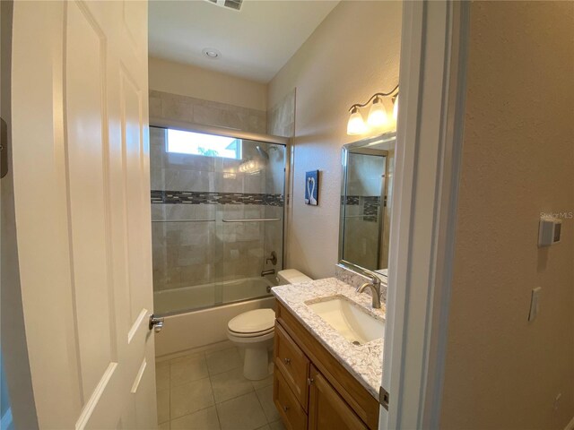 1167 Motorcoach Dr, Polk City, FL 33868 - full bathroom with tile patterned floors, vanity, toilet, combined bath / shower with glass door, and a textured wall