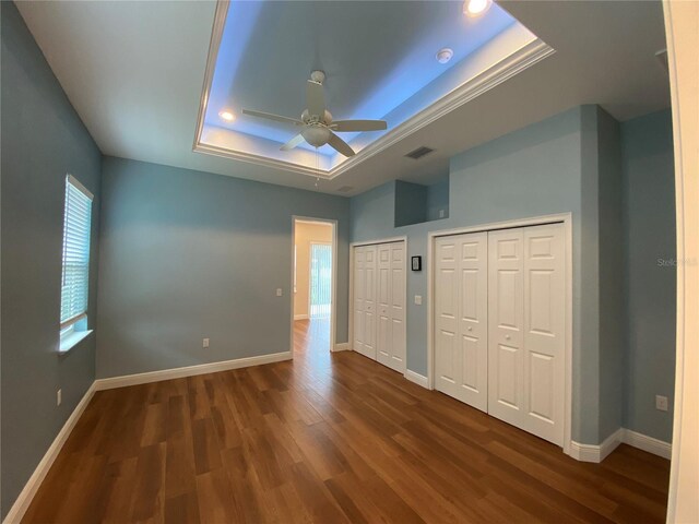 1167 Motorcoach Dr, Polk City, FL 33868 - unfurnished bedroom featuring a raised ceiling, wood finished floors, baseboards, two closets, and recessed lighting