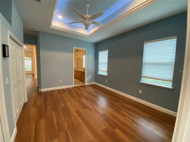 1167 Motorcoach Dr, Polk City, FL 33868 - unfurnished bedroom with a raised ceiling, wood finished floors, baseboards, and connected bathroom