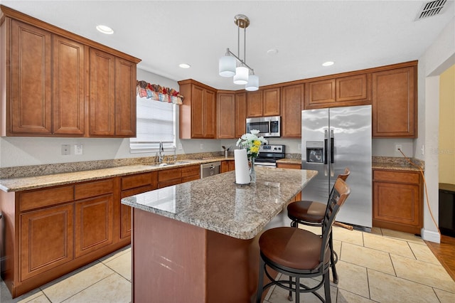 1922 Matthew Ct, Lakeland, FL 33813 - kitchen with appliances with stainless steel finishes, brown cabinetry, light stone counters, a breakfast bar area, and a center island