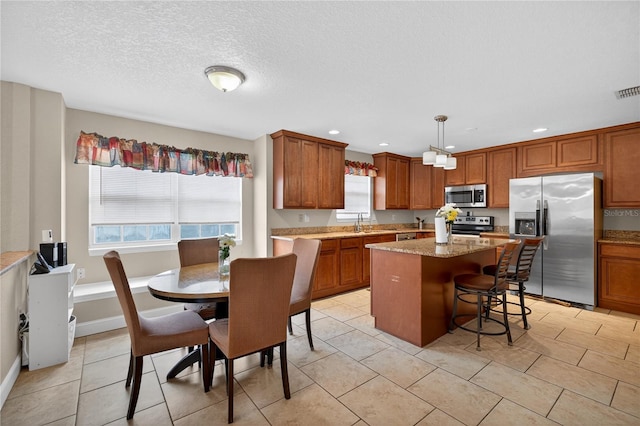 1922 Matthew Ct, Lakeland, FL 33813 - kitchen with appliances with stainless steel finishes, brown cabinetry, a kitchen island, a kitchen bar, and recessed lighting