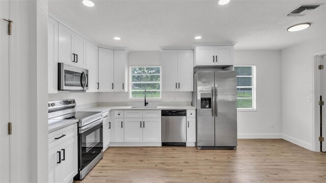 408 Sycamore St SW, Fort Meade, FL 33841 - kitchen with stainless steel appliances, a sink, light wood-type flooring, light countertops, and white cabinets
