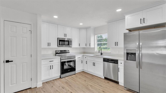 408 Sycamore St SW, Fort Meade, FL 33841 - kitchen featuring stainless steel appliances, a sink, light countertops, light wood-style flooring, and white cabinets