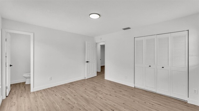 408 Sycamore St SW, Fort Meade, FL 33841 - unfurnished bedroom featuring light wood-type flooring, baseboards, a closet, and ensuite bathroom