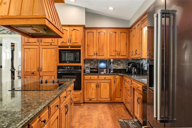 2331 D R Bryant Rd, Lakeland, FL 33810 - kitchen with black appliances, custom exhaust hood, lofted ceiling, light wood-type flooring, and brown cabinetry
