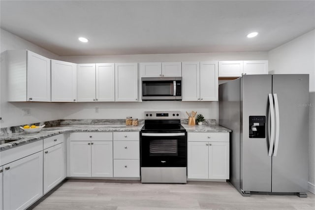 113 Patrick Henry Rd, Bartow, FL 33830 - kitchen featuring appliances with stainless steel finishes, light wood finished floors, white cabinetry, recessed lighting, and light stone counters