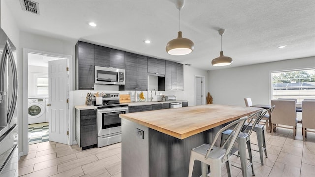 934 Point View Ln, Lakeland, FL 33813 - kitchen featuring appliances with stainless steel finishes, washer / dryer, butcher block countertops, a sink, and a breakfast bar area
