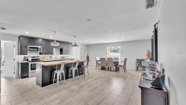 934 Point View Ln, Lakeland, FL 33813 - kitchen featuring appliances with stainless steel finishes, butcher block countertops, a breakfast bar area, a sink, and a center island