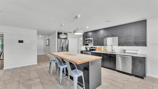 934 Point View Ln, Lakeland, FL 33813 - kitchen with appliances with stainless steel finishes, wooden counters, a sink, a kitchen bar, and hanging light fixtures
