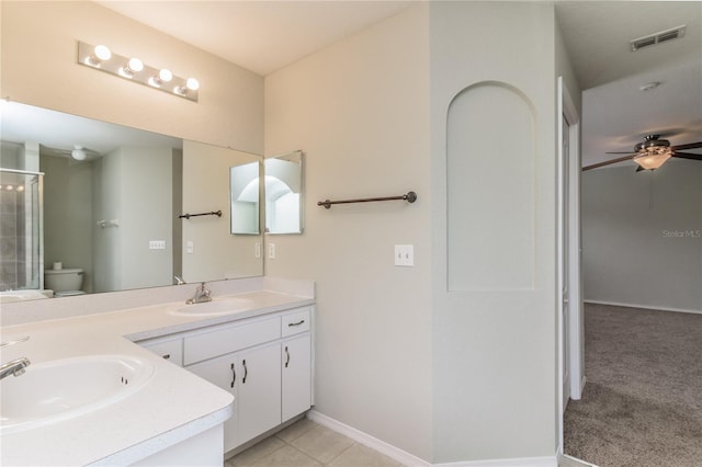 8323 Greystone Dr, Lakeland, FL 33810 - bathroom featuring a ceiling fan, toilet, an enclosed shower, double vanity, and baseboards