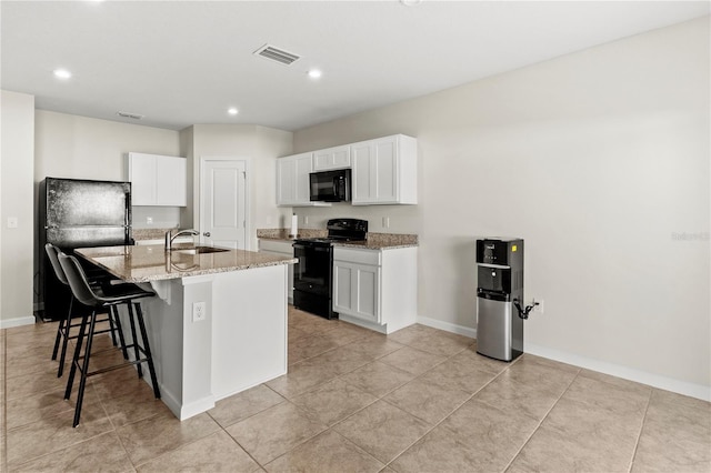 1371 Madison Cir, Haines City, FL 33844 - kitchen with black appliances, a sink, light stone counters, a breakfast bar, and white cabinetry