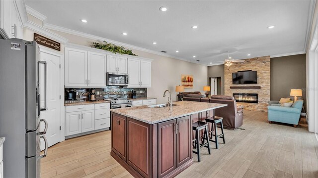 3121 Highlands By The Lake Way, Lakeland, FL 33812 - kitchen featuring appliances with stainless steel finishes, ceiling fan, white cabinets, light wood-type flooring, and a fireplace