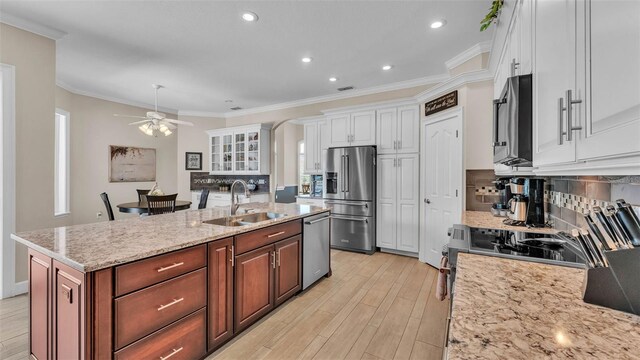 3121 Highlands By The Lake Way, Lakeland, FL 33812 - kitchen featuring appliances with stainless steel finishes, white cabinets, a ceiling fan, tasteful backsplash, and a center island with sink