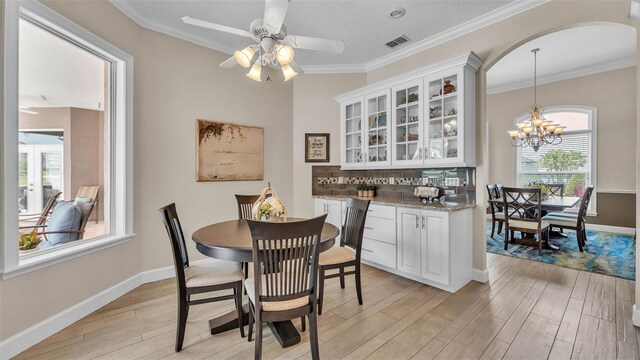 3121 Highlands By The Lake Way, Lakeland, FL 33812 - dining area with arched walkways, light wood-style flooring, a chandelier, a ceiling fan, and crown molding