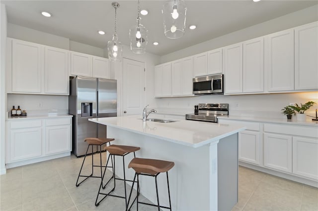 1754 Sanibel Dr, Davenport, FL 33896 - kitchen with stainless steel appliances, a sink, light tile patterned floors, a breakfast bar area, and white cabinetry