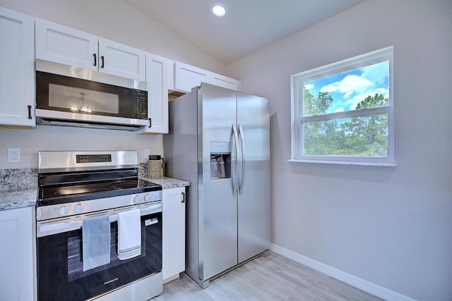 2438 W Wellston Rd, Avon Park, FL 33825 - kitchen with stainless steel appliances, light wood finished floors, white cabinets, light stone countertops, and lofted ceiling