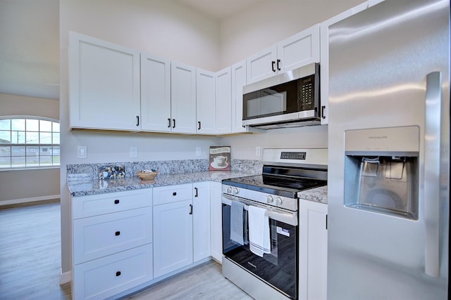 2438 W Wellston Rd, Avon Park, FL 33825 - kitchen featuring appliances with stainless steel finishes, light wood-style flooring, light stone countertops, white cabinetry, and baseboards