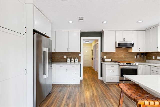 6819 Broken Arrow Trl S, Lakeland, FL 33813 - kitchen featuring appliances with stainless steel finishes, light countertops, wood finished floors, tasteful backsplash, and white cabinetry