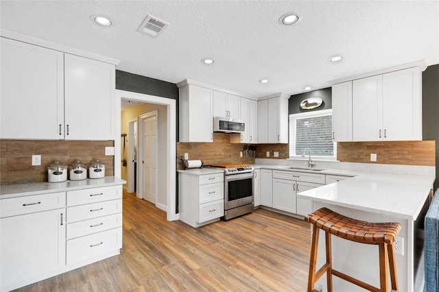 6819 Broken Arrow Trl S, Lakeland, FL 33813 - kitchen with stainless steel appliances, a peninsula, decorative backsplash, light countertops, and recessed lighting