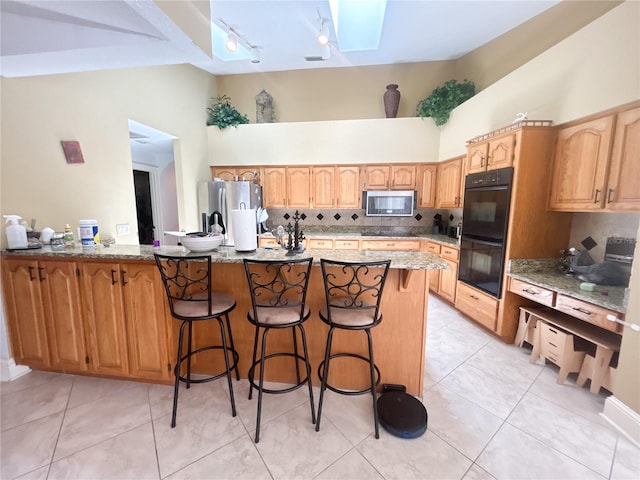 1909 Masters Way, Plant City, FL 33566 - kitchen featuring black appliances, high vaulted ceiling, a skylight, rail lighting, and backsplash