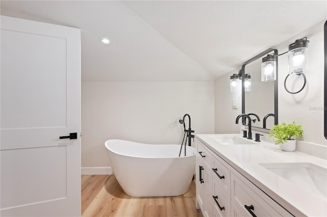 818 Woodward St, Lakeland, FL 33803 - full bath with wood finished floors, double vanity, a freestanding bath, vaulted ceiling, and baseboards