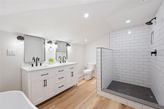 818 Woodward St, Lakeland, FL 33803 - full bath with tiled shower, wood finished floors, double vanity, toilet, and lofted ceiling