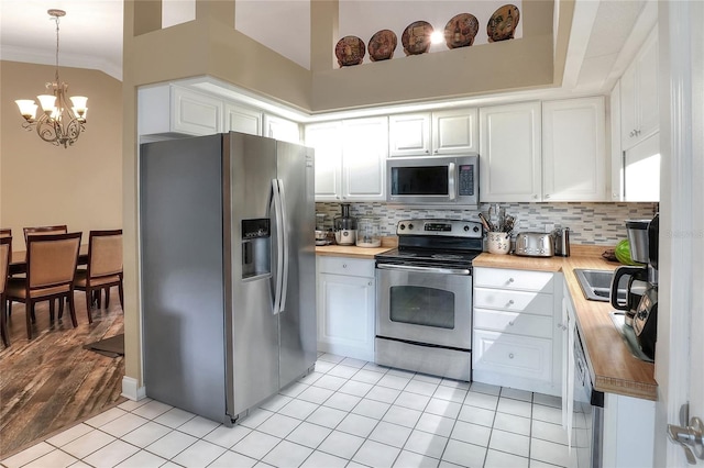 1300 Ariana Woods Cir, Auburndale, FL 33823 - kitchen featuring appliances with stainless steel finishes, butcher block counters, a chandelier, decorative backsplash, and crown molding