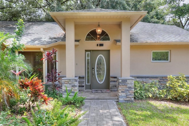 1300 Ariana Woods Cir, Auburndale, FL 33823 - doorway to property with a shingled roof, stucco siding, and stone siding